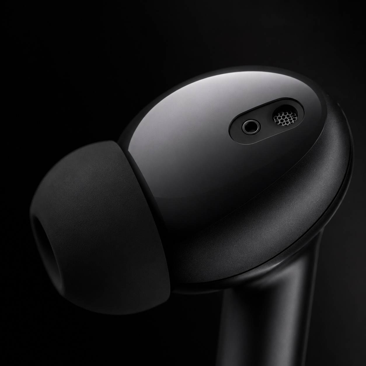 Close-up of wireless earbud featuring built-in microphone, ergonomic in-ear design, soft silicone ear tip, and premium matte black finish for calls and music.
